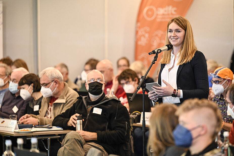 ADFC-Bundeshauptversammlung 2022 Rebecca Peters steht zwischen den sitzenden Delegierten