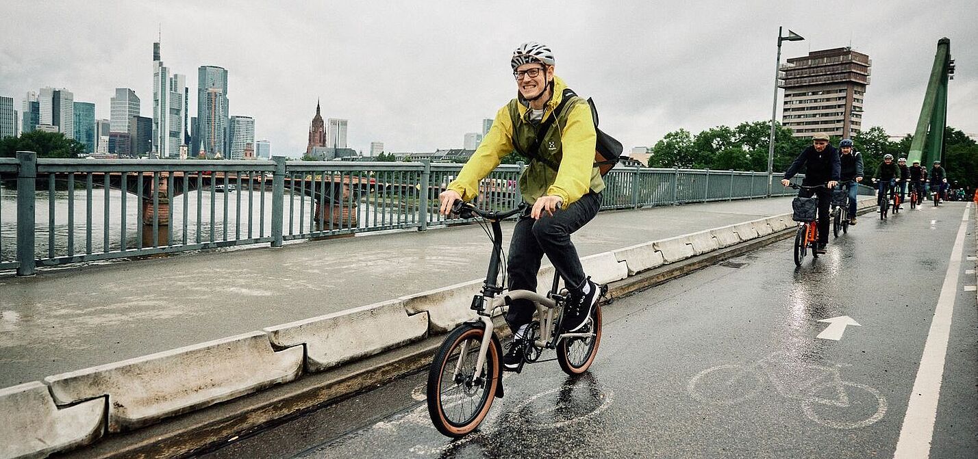 Radfahrer auf einem Brompton G-Line bei regenerischem Wetter in der Stadt. 