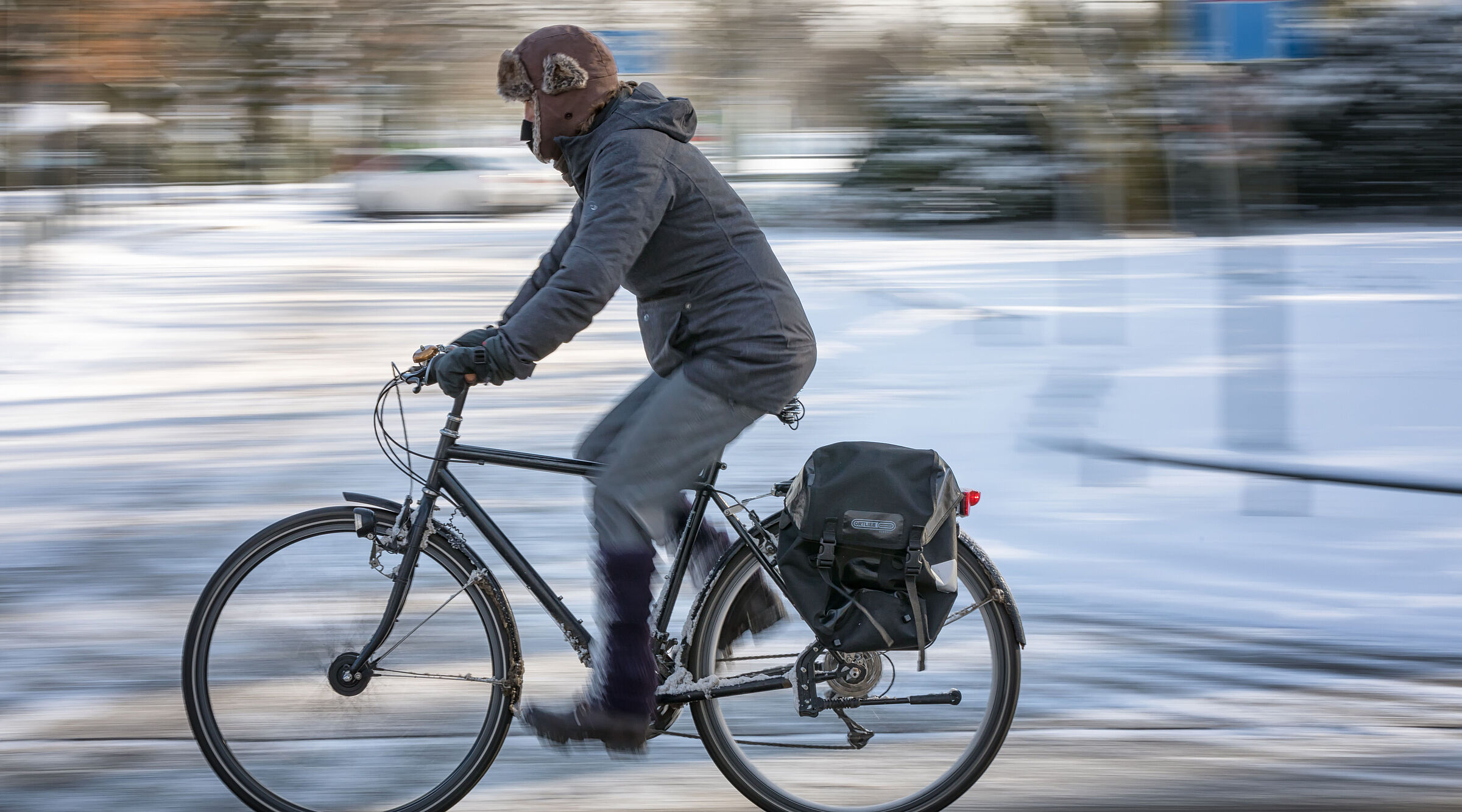 Mann fährt auf ungeräumten Radweg im Winter