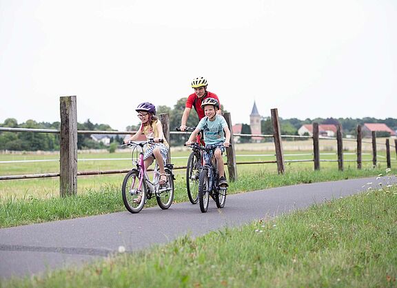 Opa mit zwei Kindern auf Fahrradweg im ländlicher Umgebung