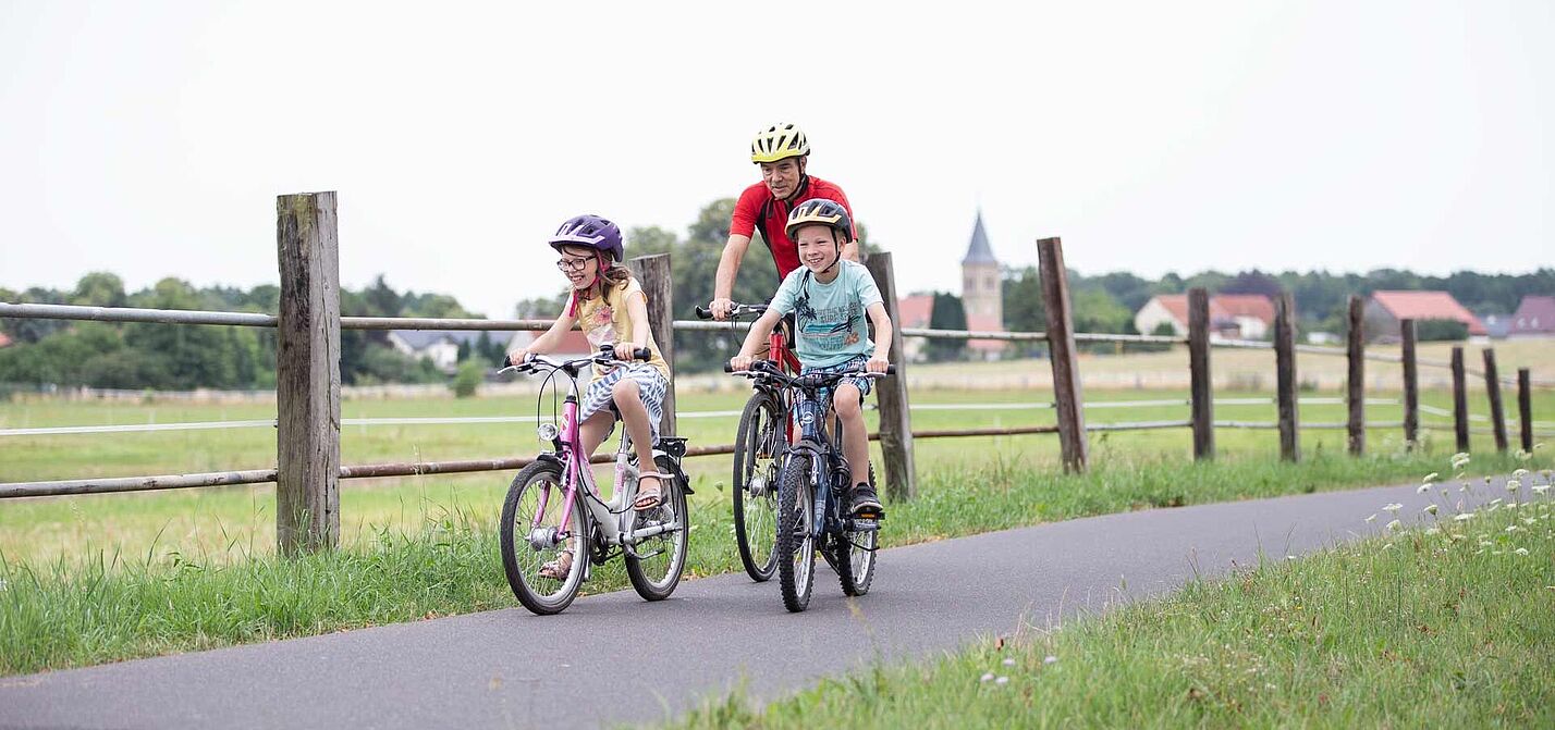 Opa mit zwei Kindern auf Fahrradweg im ländlicher Umgebung